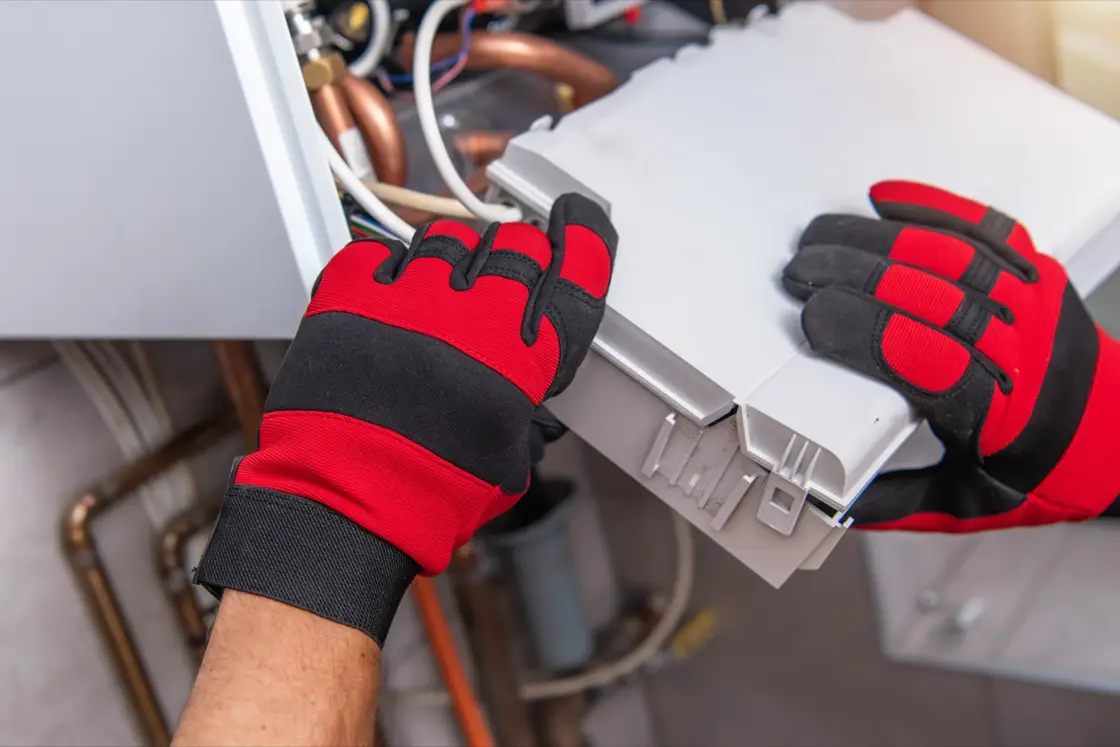 HVAC technician performing maintenance on heat pump equipment and wiring